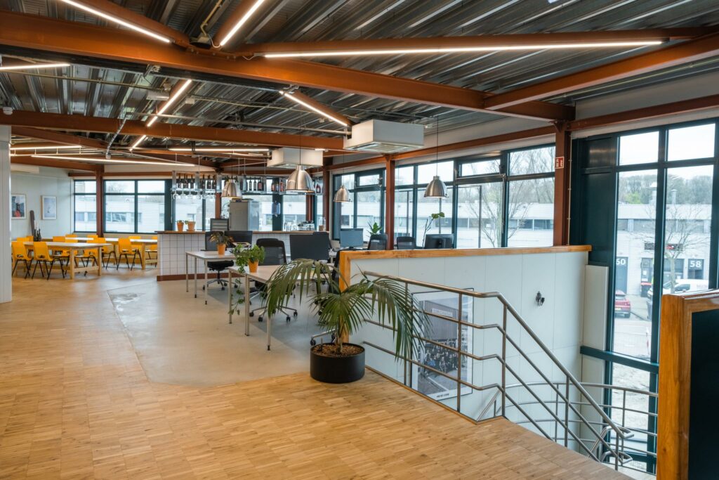 Moderne kantoorruimte aan de Johan van Hasseltweg met open werkplekken, gele eetkamerstoelen en grote ramen voor natuurlijk licht.